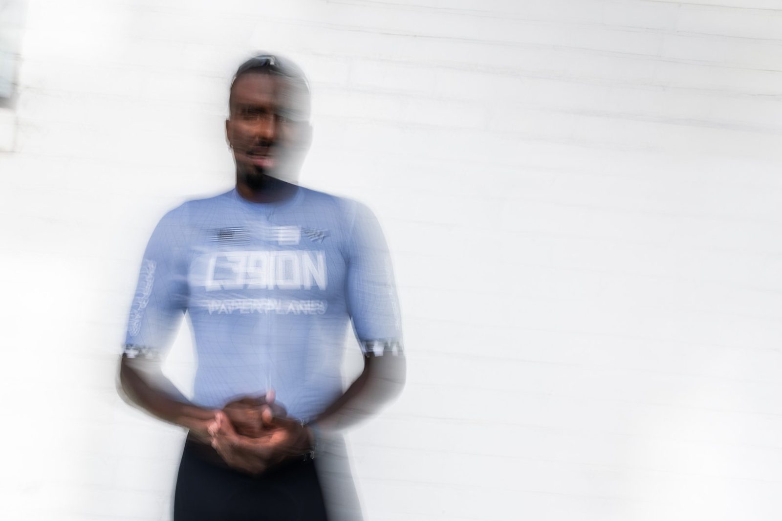 Justin Williams in the light blue L39ION Paper Planes race jersey, caught in motion against a white wall