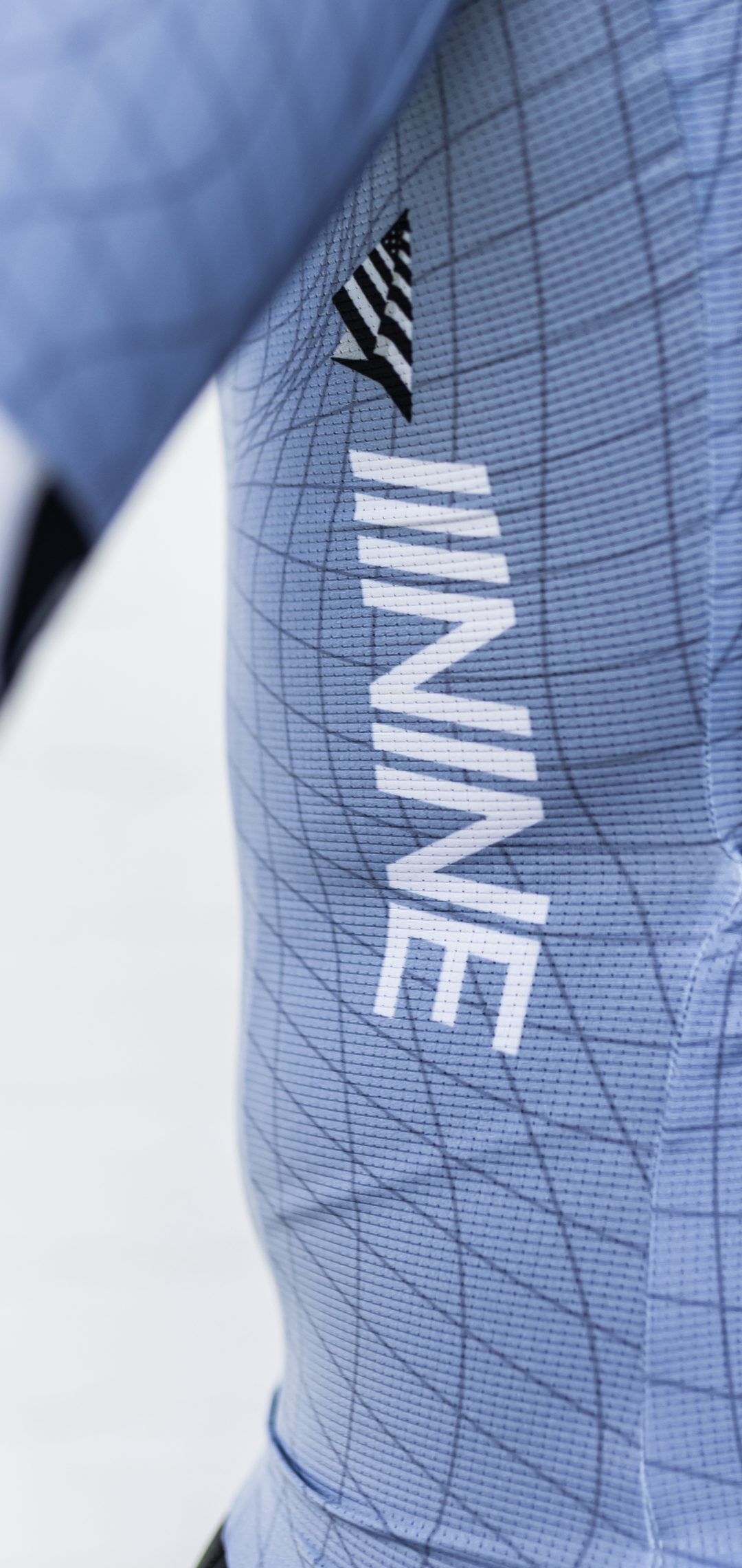 Close-up of the light blue L39ION race jersey with the IIININE wordmark and Paper Planes mark